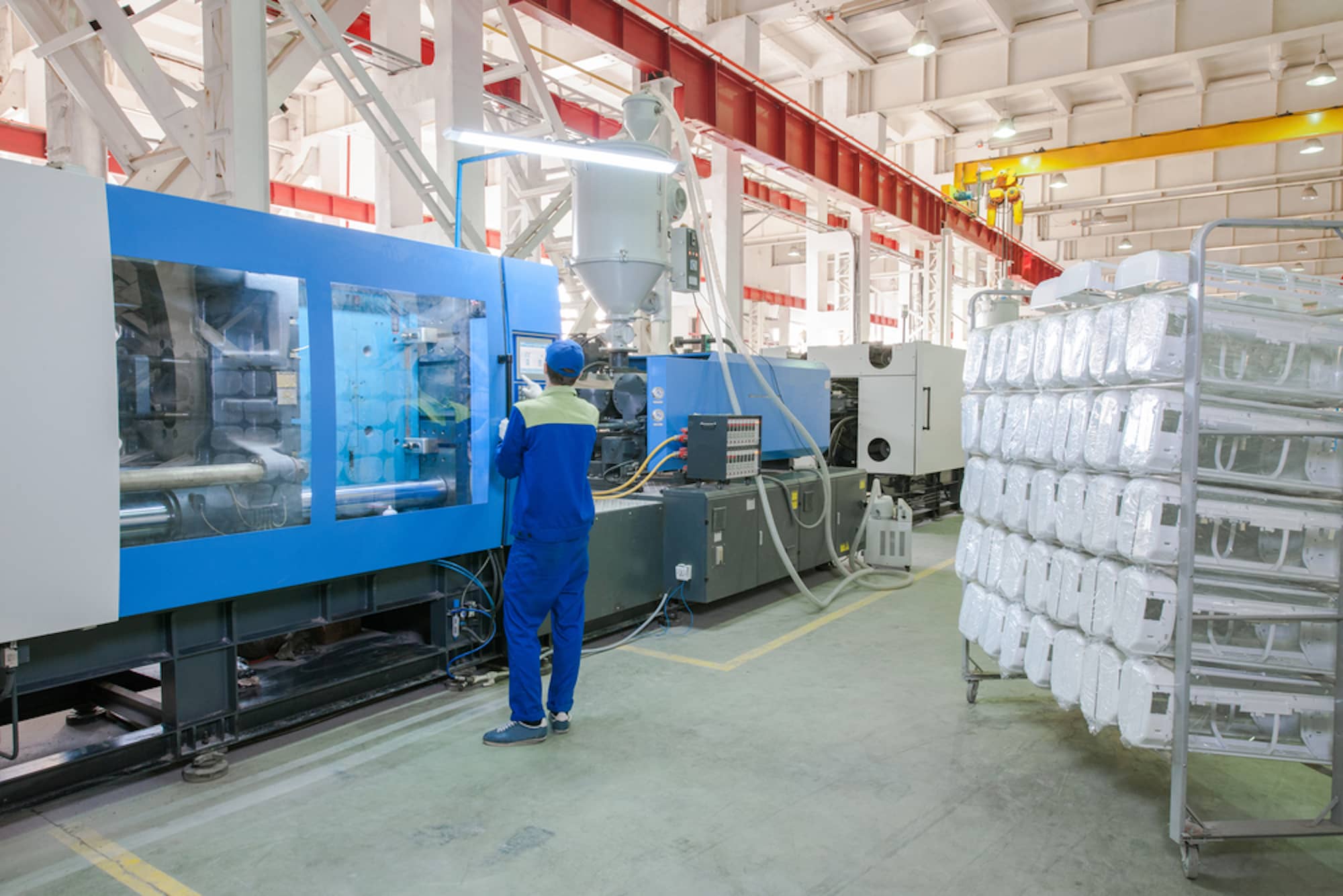 history of plastic injection molding factory floor man in blue working at machine
